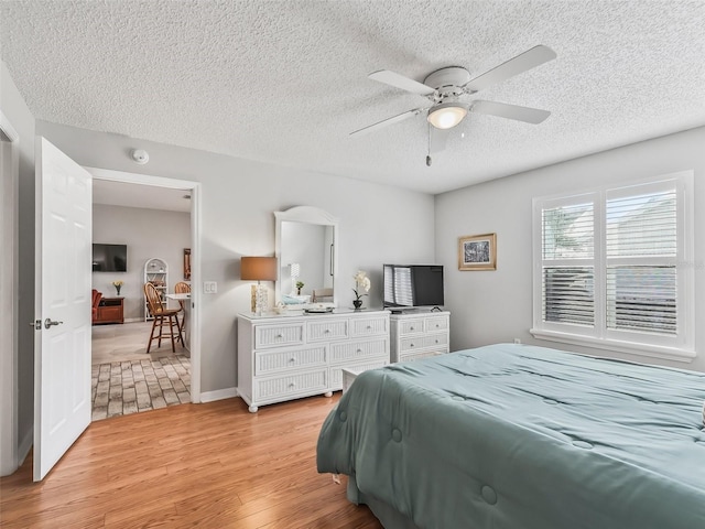 bedroom featuring ceiling fan, a textured ceiling, and light wood-type flooring