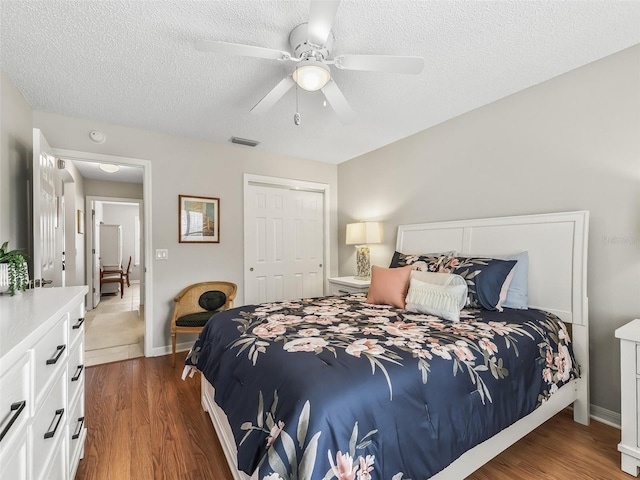 bedroom with a closet, a textured ceiling, dark hardwood / wood-style floors, and ceiling fan