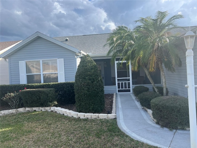 view of front of property with a front yard and a sunroom