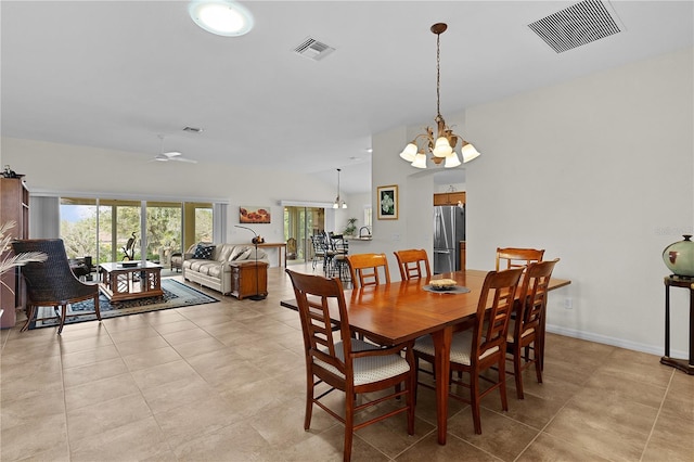 dining area with ceiling fan with notable chandelier, vaulted ceiling, and light tile patterned floors