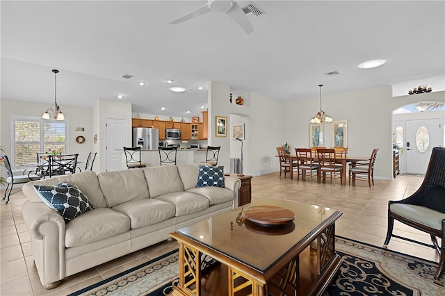 living room featuring ceiling fan with notable chandelier and light tile patterned floors