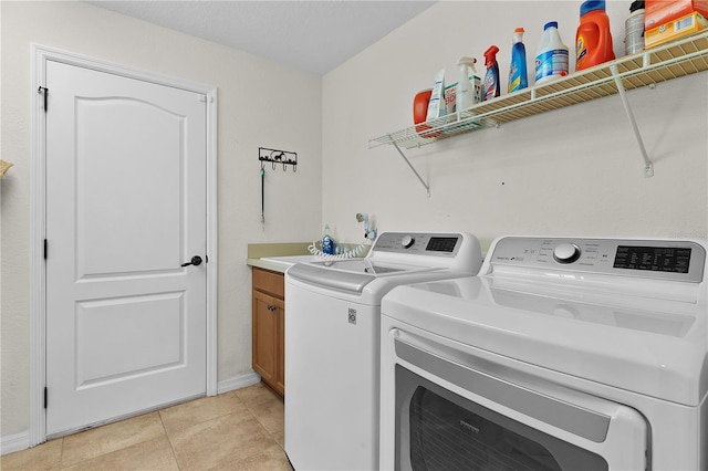 laundry area with light tile patterned flooring, cabinets, and separate washer and dryer