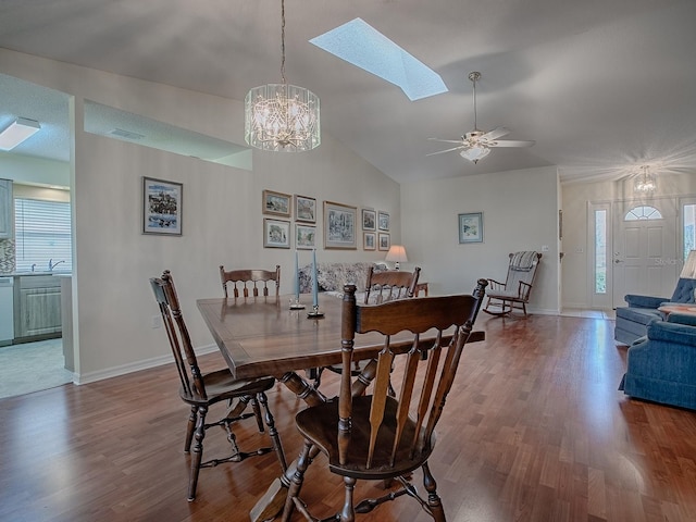 dining room with lofted ceiling with skylight, ceiling fan with notable chandelier, sink, and hardwood / wood-style floors