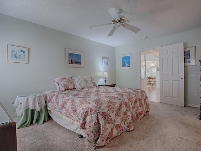 carpeted bedroom featuring ceiling fan and a textured ceiling