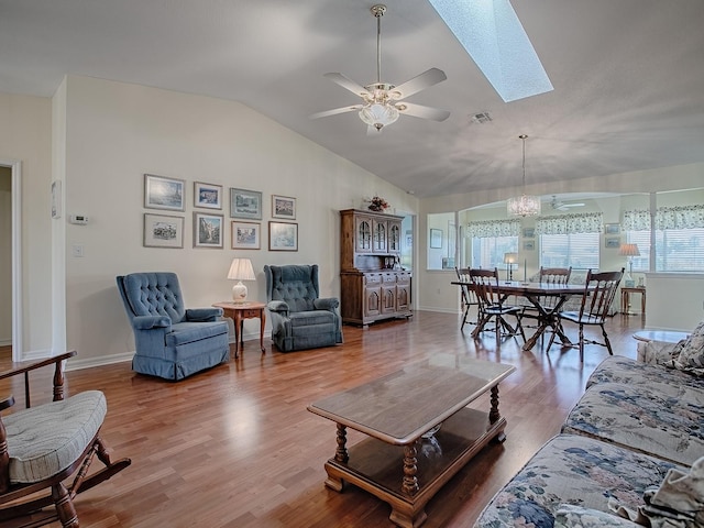 living room with wood-type flooring, vaulted ceiling with skylight, and ceiling fan