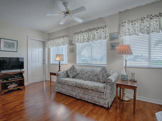 living room featuring ceiling fan, hardwood / wood-style flooring, and a textured ceiling