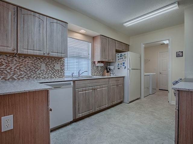 kitchen featuring washer and dryer, sink, decorative backsplash, white appliances, and a textured ceiling