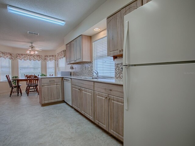 kitchen with sink, white appliances, ceiling fan, tasteful backsplash, and light brown cabinets