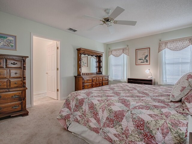 bedroom featuring ceiling fan, light colored carpet, and a textured ceiling