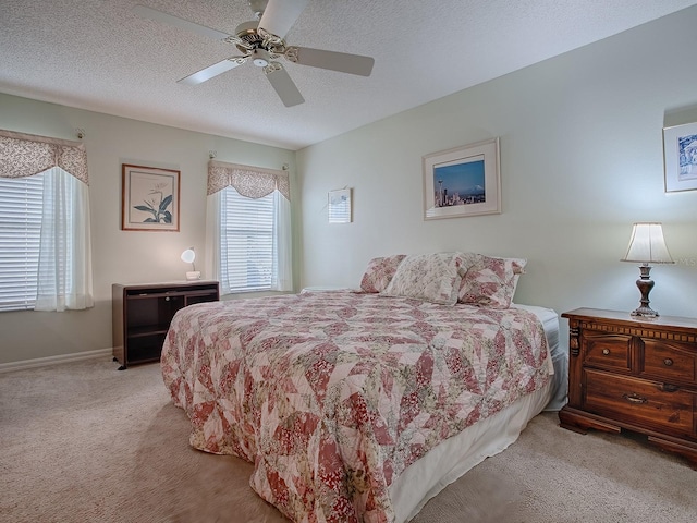 bedroom with ceiling fan, light carpet, and a textured ceiling