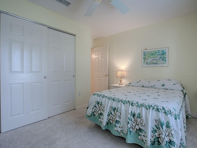 bedroom with light colored carpet, ceiling fan, and a closet