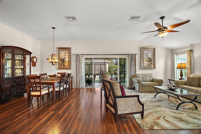 living room featuring dark hardwood / wood-style flooring, ceiling fan with notable chandelier, vaulted ceiling, and a healthy amount of sunlight