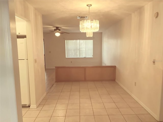 empty room featuring light tile patterned floors, baseboards, visible vents, and ceiling fan with notable chandelier