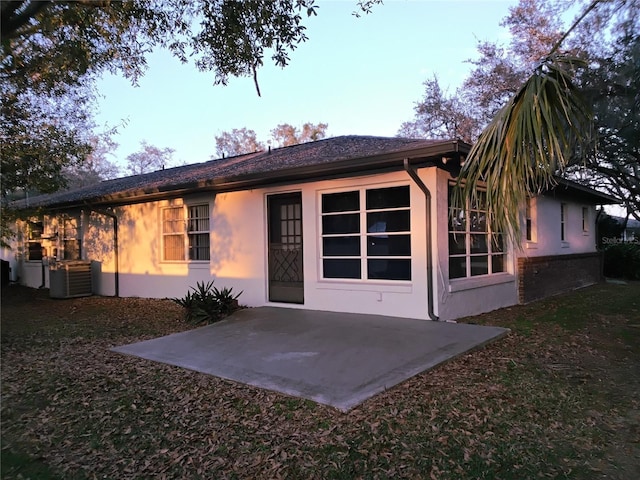 back of property with stucco siding, central AC, and a patio