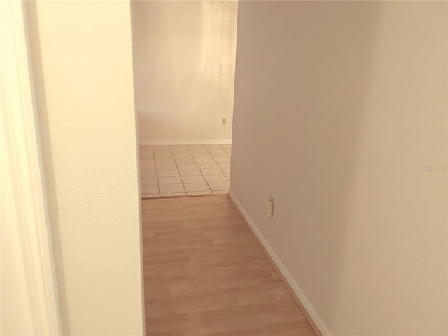 hallway featuring baseboards and light wood finished floors