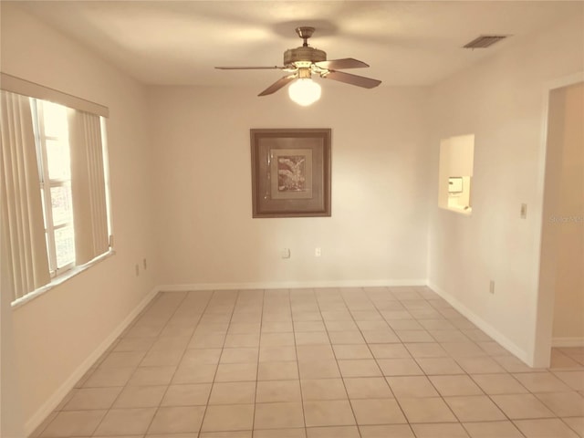 spare room featuring a ceiling fan, light tile patterned flooring, visible vents, and baseboards