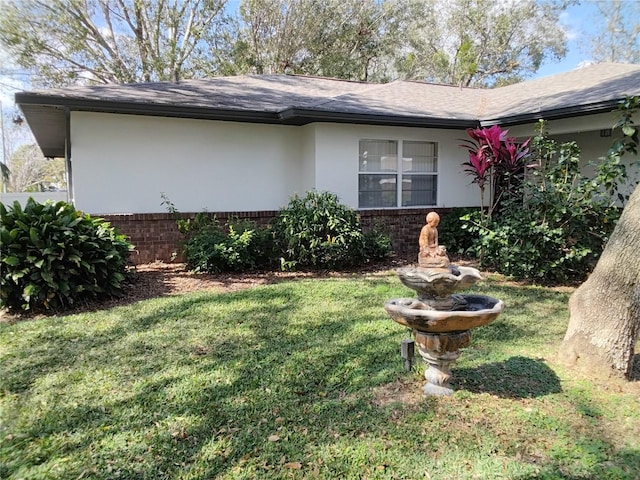 view of property exterior with brick siding, a lawn, and stucco siding