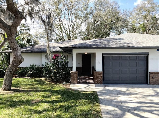 single story home featuring brick siding, a shingled roof, a front yard, a garage, and driveway