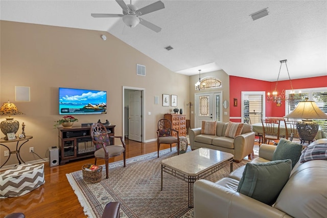 living room featuring ceiling fan with notable chandelier, vaulted ceiling, dark hardwood / wood-style floors, and a textured ceiling