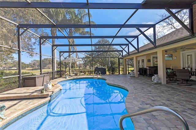 view of swimming pool with ceiling fan, a lanai, and a patio