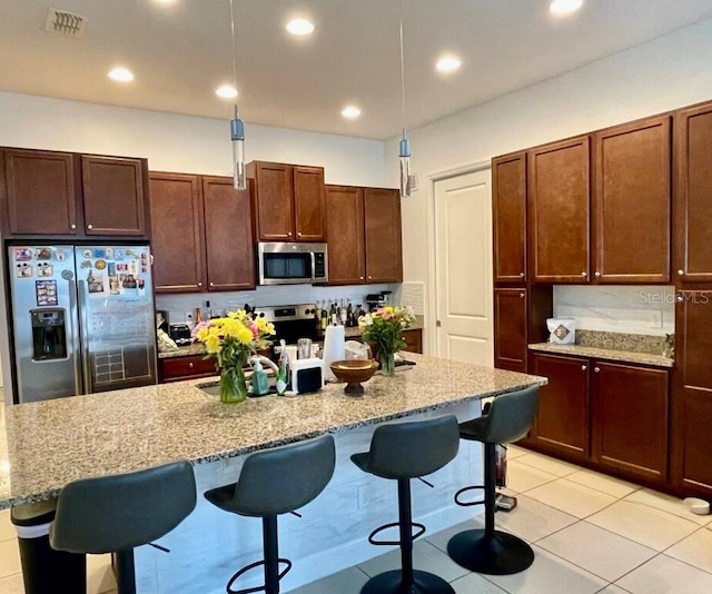 kitchen with stainless steel appliances, decorative light fixtures, a breakfast bar, and a kitchen island