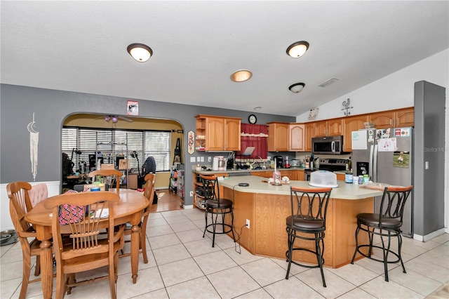 kitchen featuring vaulted ceiling, appliances with stainless steel finishes, a kitchen bar, and a center island