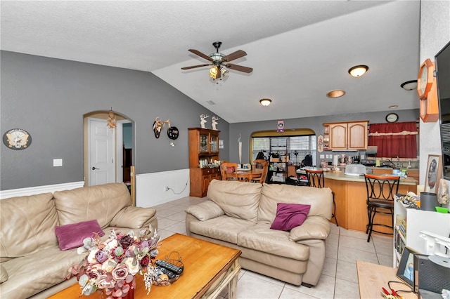 tiled living room with lofted ceiling, a textured ceiling, and ceiling fan