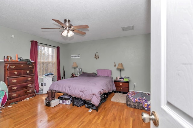 bedroom with ceiling fan, hardwood / wood-style floors, and a textured ceiling