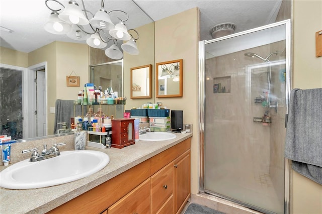 bathroom with a chandelier, vanity, and a shower with shower door