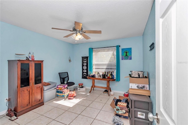 recreation room featuring light tile patterned flooring, a textured ceiling, and ceiling fan