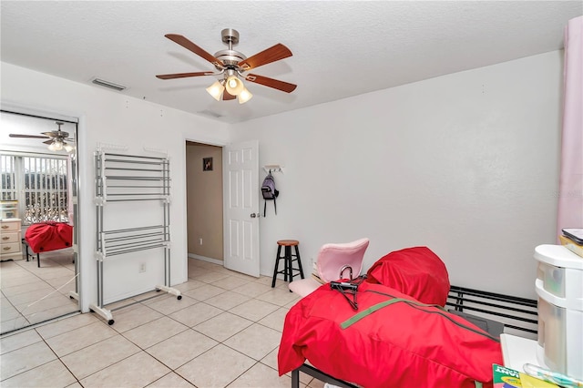 bedroom featuring light tile patterned floors, a textured ceiling, and ceiling fan