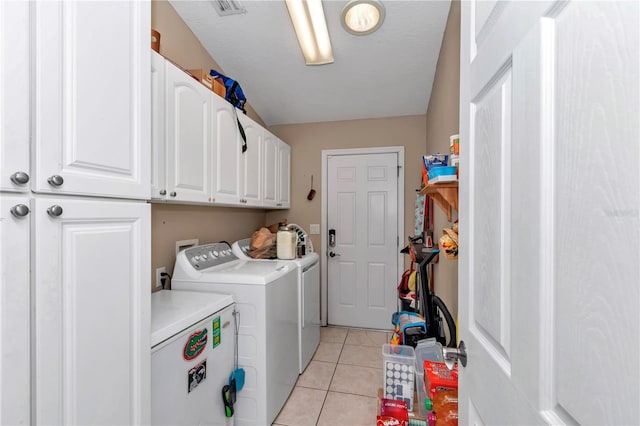 washroom featuring cabinets, washing machine and dryer, light tile patterned floors, and a textured ceiling