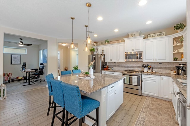 kitchen featuring decorative light fixtures, white cabinetry, a kitchen breakfast bar, a center island, and stainless steel appliances