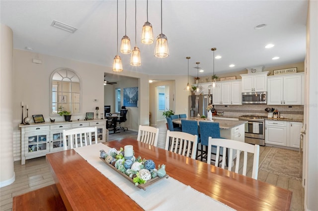 dining space with ceiling fan and light wood-type flooring