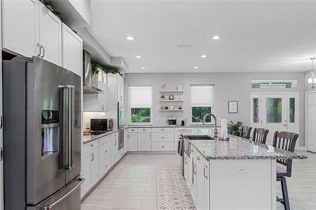 kitchen with white cabinetry, stainless steel appliances, a kitchen island with sink, and a breakfast bar area