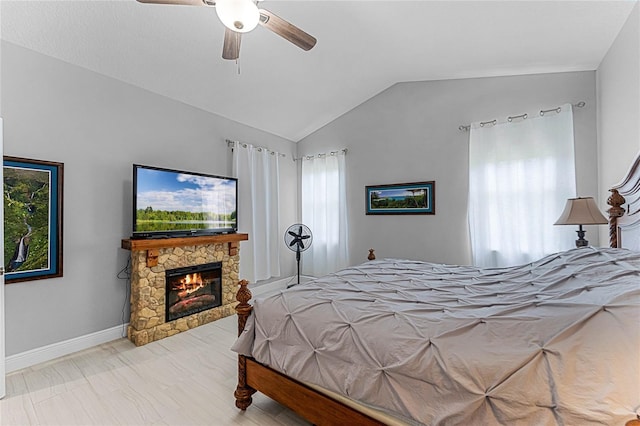 bedroom featuring ceiling fan, lofted ceiling, and a stone fireplace