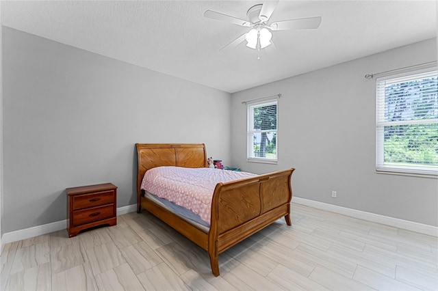 bedroom featuring ceiling fan, multiple windows, and a textured ceiling