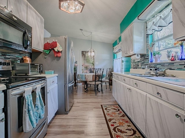11915 Crk 680, Webster, FL 33597 - kitchen featuring an inviting chandelier, decorative light fixtures, light hardwood / wood-style flooring, stainless steel appliances, and backsplash