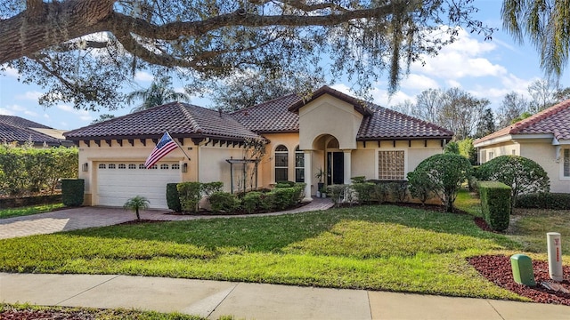 mediterranean / spanish house featuring a garage and a front yard