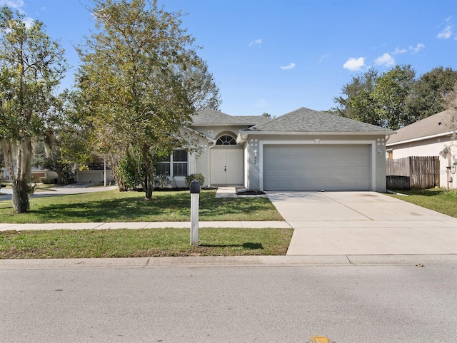 view of front facade featuring stucco siding, concrete driveway, an attached garage, a front yard, and fence