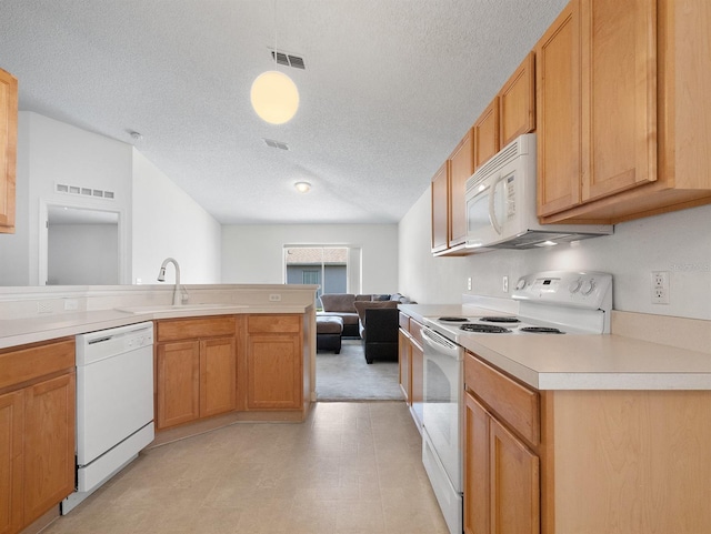 kitchen featuring white appliances, light countertops, a sink, and visible vents