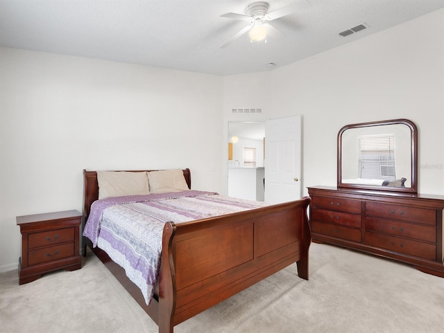 bedroom with ceiling fan, a textured ceiling, visible vents, and light colored carpet