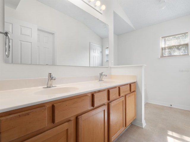 bathroom featuring double vanity, baseboards, vaulted ceiling, and a sink