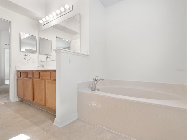 bathroom with a garden tub, vanity, and baseboards