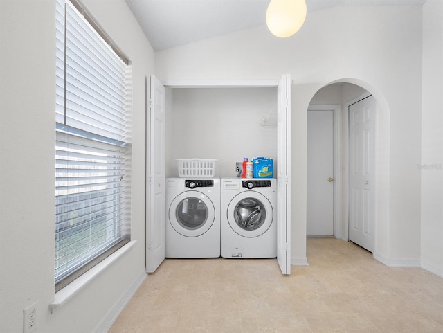 washroom featuring arched walkways, laundry area, separate washer and dryer, and baseboards