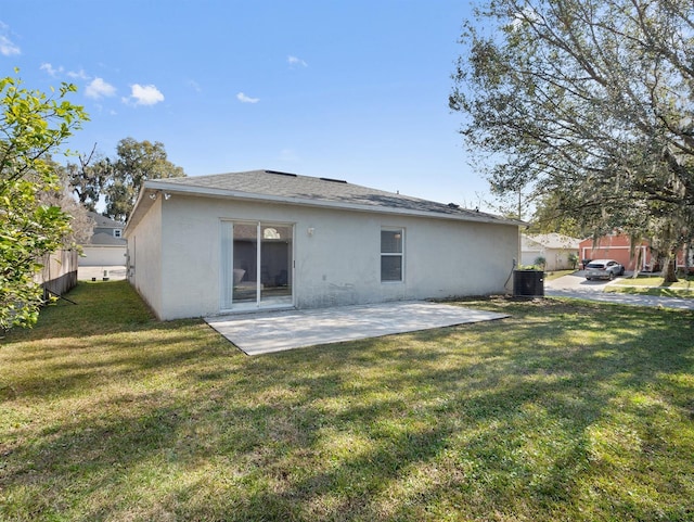 rear view of house with stucco siding, a yard, central AC unit, and a patio