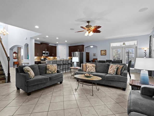 tiled living room with ceiling fan with notable chandelier