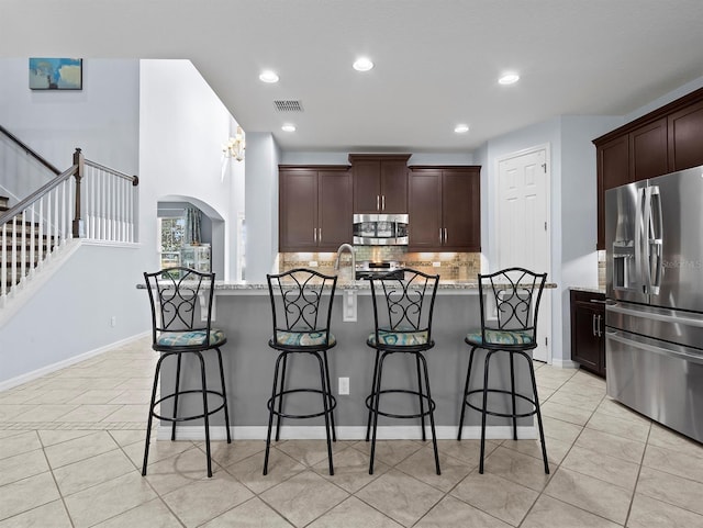 887 Daisy Hill Ct, Apopka, FL 32712 - kitchen with light stone counters, stainless steel appliances, a kitchen island with sink, and tasteful backsplash
