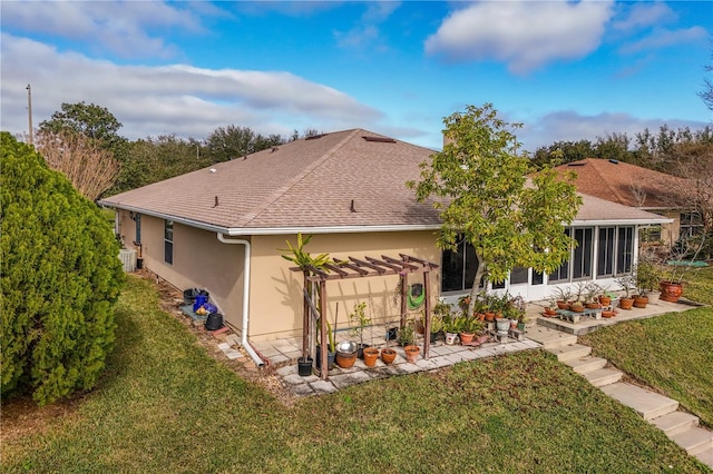 back of house with a pergola, a sunroom, and a lawn