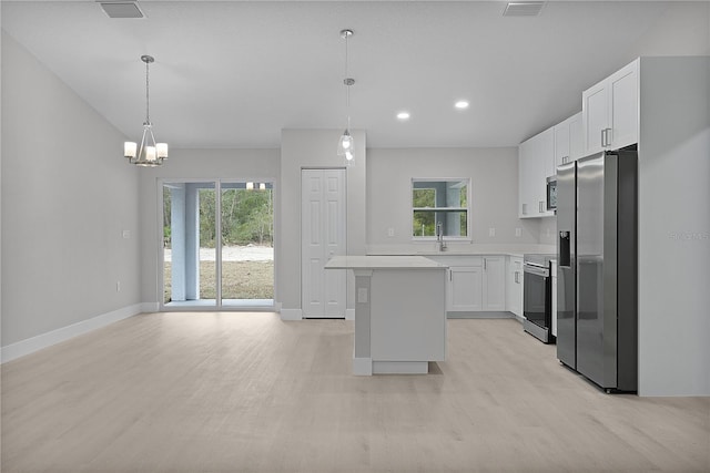 kitchen with hanging light fixtures, a kitchen island, a wealth of natural light, stainless steel appliances, and white cabinets